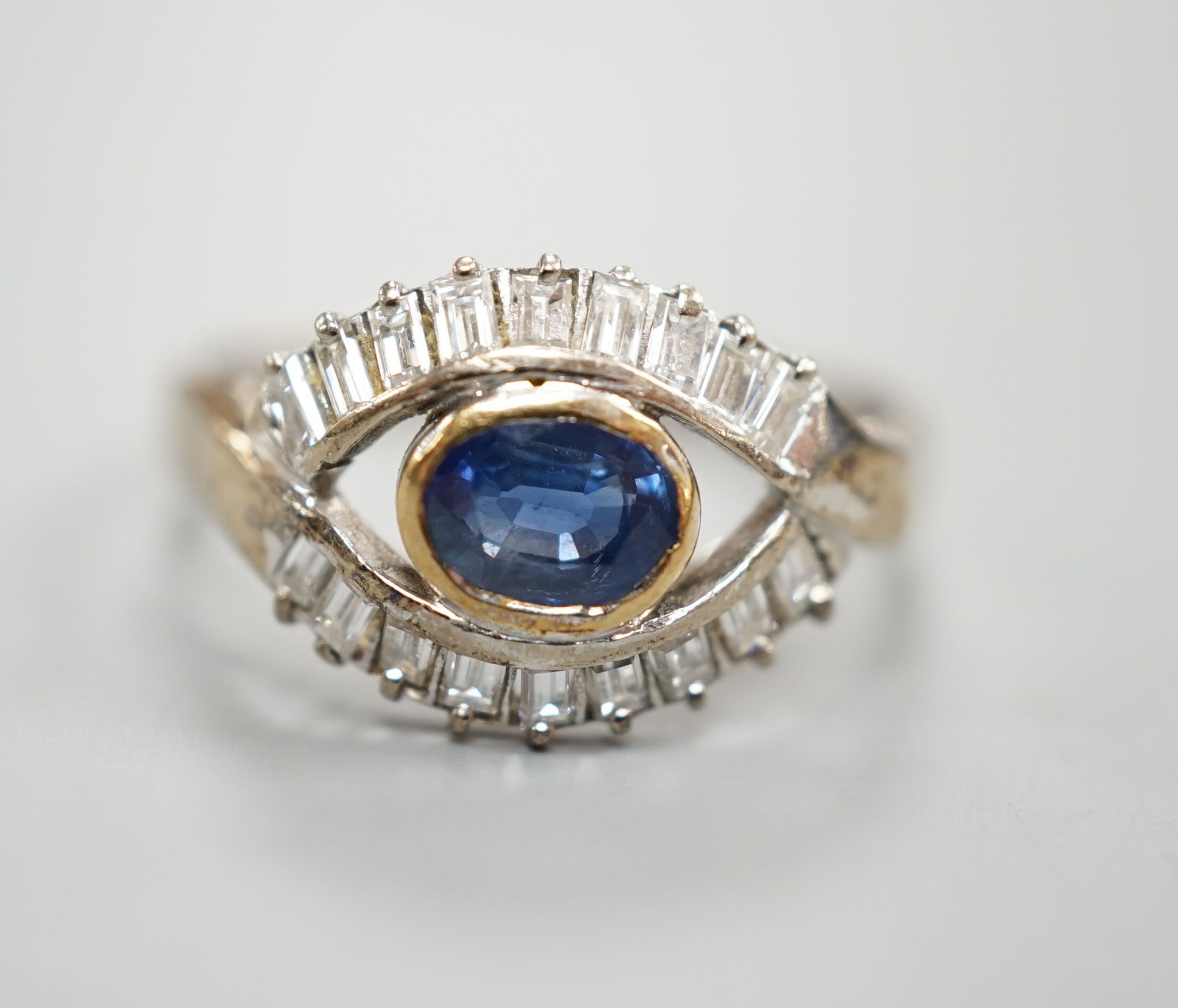 A modern 585 white metal sapphire and baguette cut diamond cluster set 'eye' ring, size T, gross 4 grams.